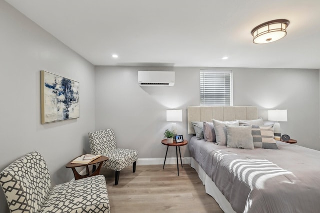 bedroom featuring recessed lighting, a wall mounted air conditioner, wood finished floors, and baseboards