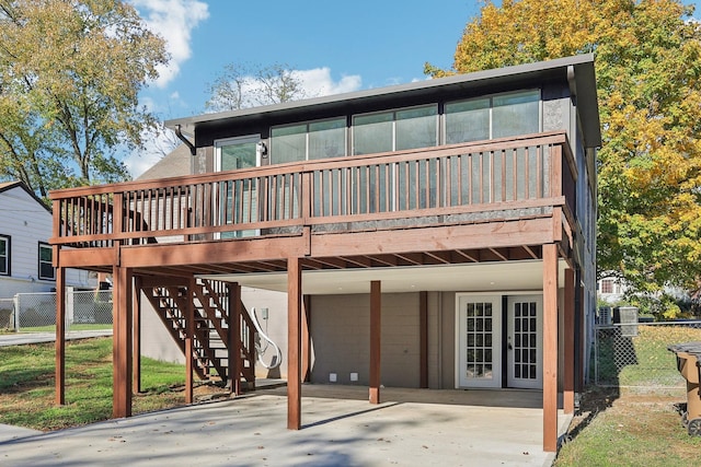 rear view of property featuring a carport, french doors, fence, and stairs