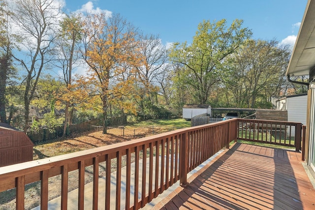 wooden terrace with a storage shed, a fenced backyard, and an outdoor structure