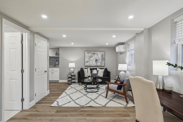 living room featuring recessed lighting, a wall unit AC, baseboards, and wood finished floors