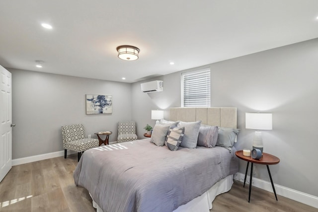 bedroom with recessed lighting, a wall mounted air conditioner, light wood-style flooring, and baseboards