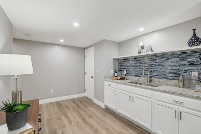 kitchen featuring a sink, white cabinetry, light wood-type flooring, open shelves, and tasteful backsplash