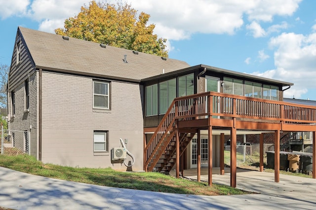 rear view of house featuring a deck, brick siding, a sunroom, stairway, and ac unit