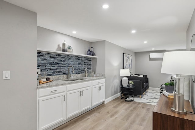 bar featuring light wood-style flooring, backsplash, a sink, and recessed lighting