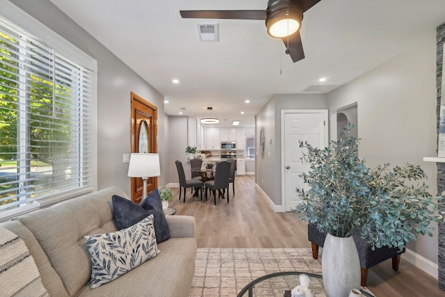 living area with visible vents, baseboards, light wood-style flooring, ceiling fan, and recessed lighting