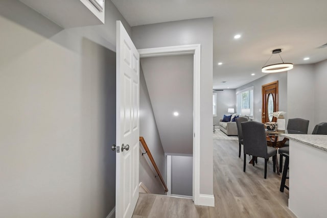 hall with recessed lighting, baseboards, light wood-style flooring, and an upstairs landing