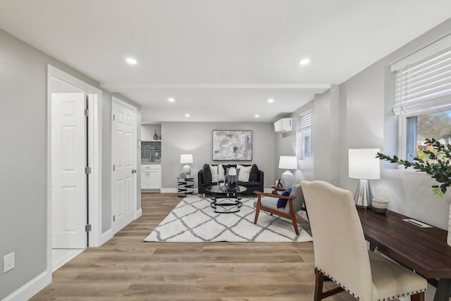 living room featuring light wood-style flooring, baseboards, an AC wall unit, and recessed lighting