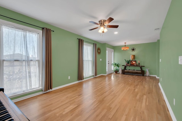 unfurnished room featuring light wood-style floors, ceiling fan, visible vents, and baseboards