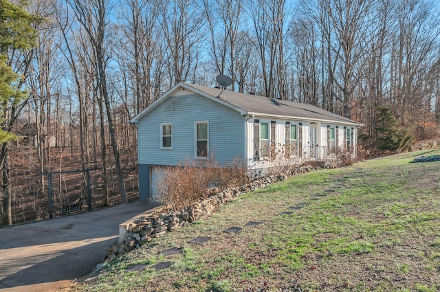 view of side of property featuring a yard, driveway, and an attached garage