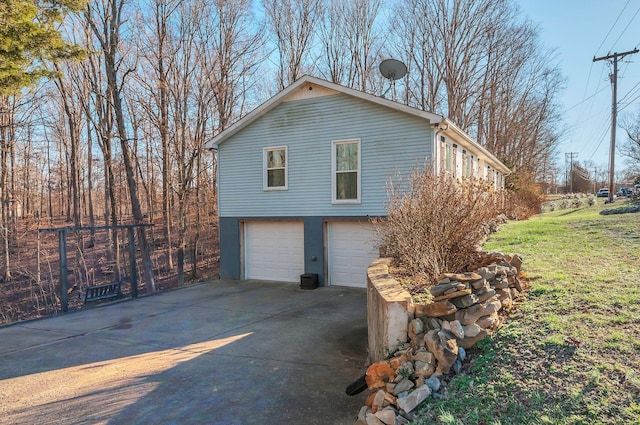 view of side of home with driveway, an attached garage, and a lawn