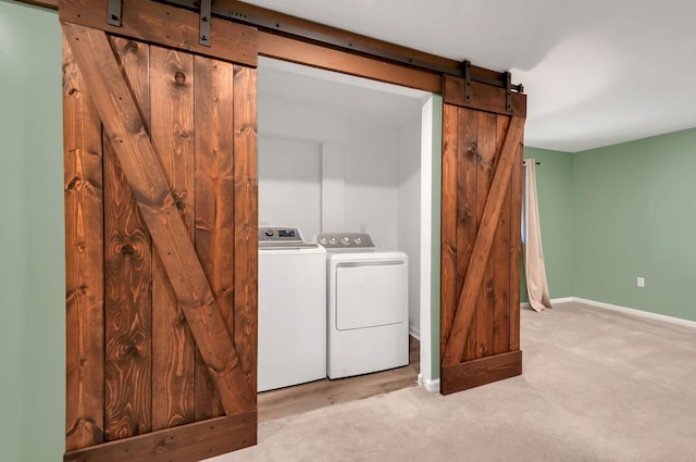 laundry area with carpet, a barn door, washing machine and dryer, laundry area, and baseboards