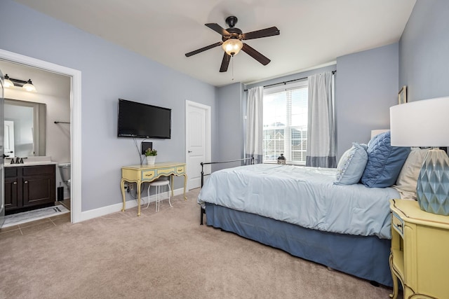 bedroom with a ceiling fan, light carpet, a sink, ensuite bath, and baseboards