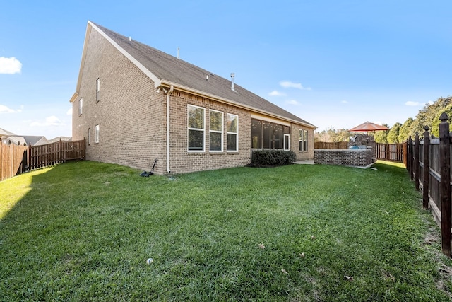 rear view of house featuring brick siding, a lawn, and a fenced backyard