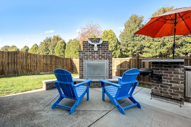 view of patio with an outdoor brick fireplace and a fenced backyard