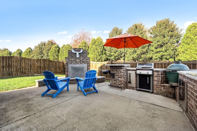 view of patio featuring an outdoor brick fireplace, a grill, a fenced backyard, and area for grilling