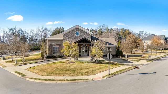 view of front facade with a front yard, stone siding, and driveway