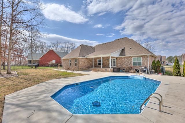 view of swimming pool with a patio, cooling unit, fence, a fenced in pool, and a lawn