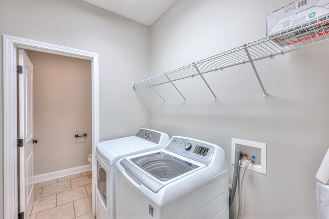 washroom featuring laundry area, light tile patterned floors, separate washer and dryer, and baseboards