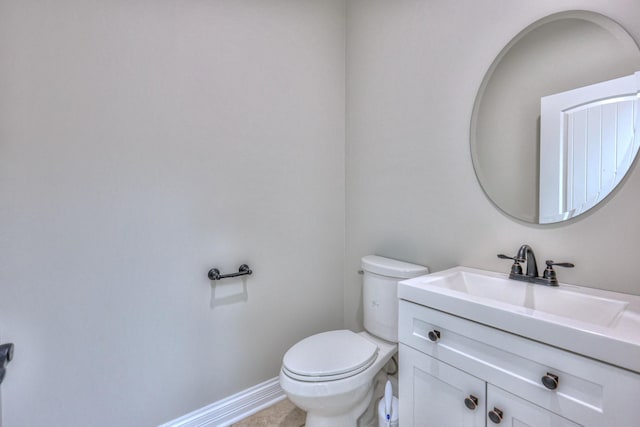 bathroom featuring toilet, vanity, and baseboards