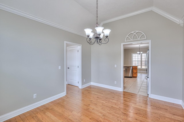 empty room featuring crown molding, light wood-style floors, an inviting chandelier, and vaulted ceiling