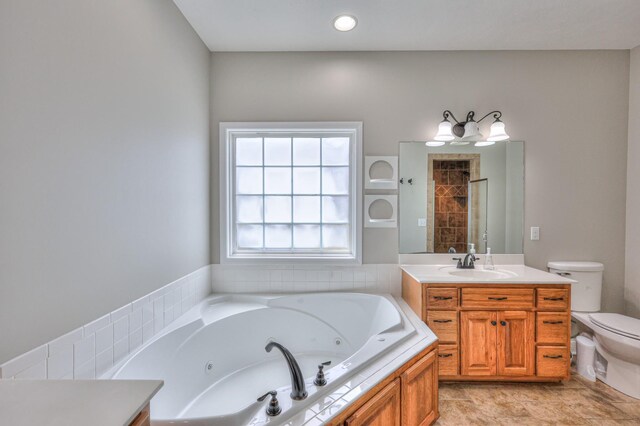 bathroom featuring vanity, toilet, a whirlpool tub, and a tile shower
