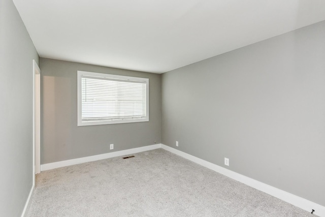 empty room featuring carpet flooring, visible vents, and baseboards