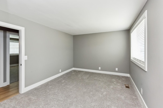 carpeted spare room with visible vents and baseboards