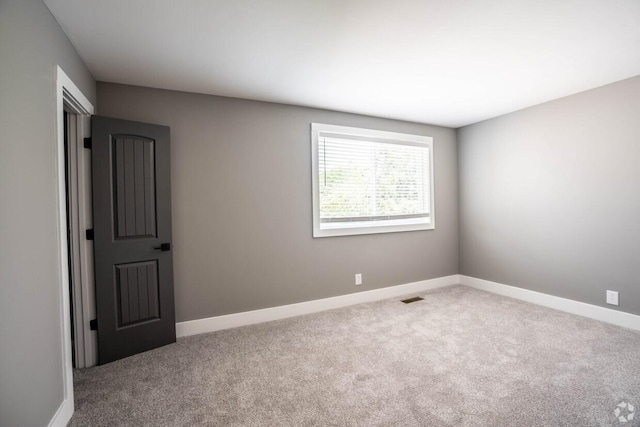 empty room featuring carpet, visible vents, and baseboards