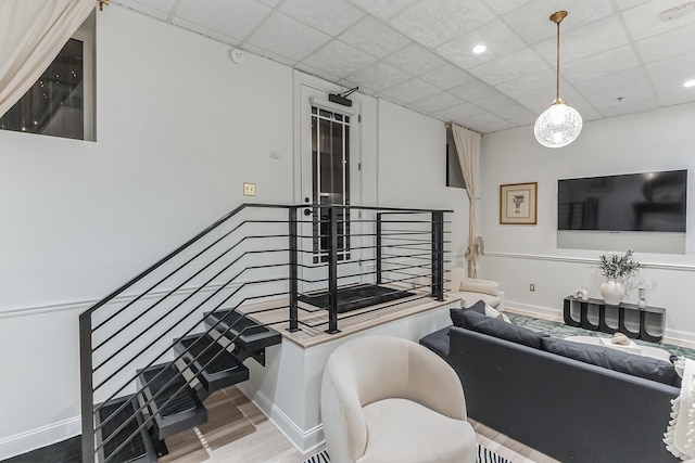 living area with recessed lighting, a drop ceiling, baseboards, and wood finished floors