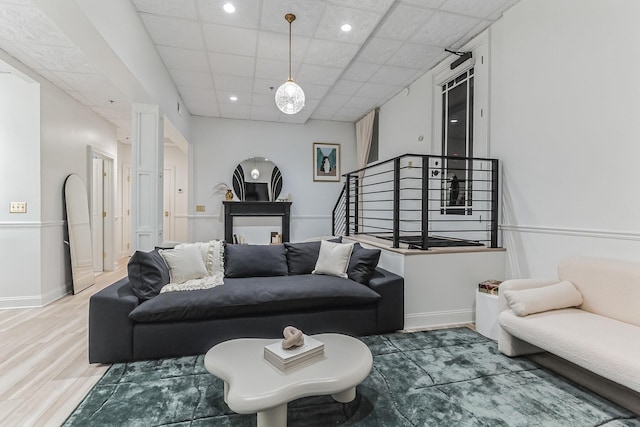 living area with a drop ceiling, stairway, baseboards, and wood finished floors