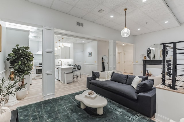 living area with arched walkways, recessed lighting, visible vents, stairway, and light wood-type flooring