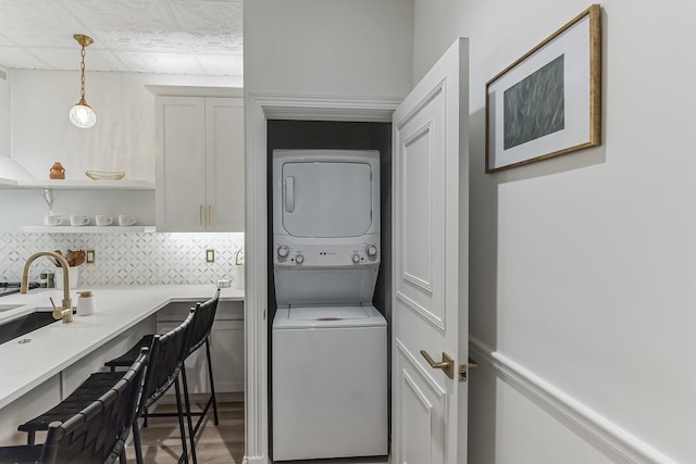 laundry room with stacked washer and dryer, wood finished floors, and laundry area