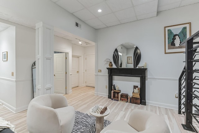 sitting room with a paneled ceiling, visible vents, light wood-style flooring, and baseboards