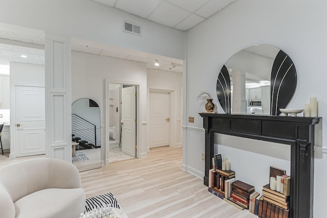 sitting room featuring light wood finished floors, visible vents, and a drop ceiling