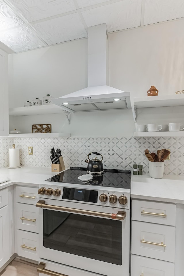 kitchen with high end range, light countertops, wall chimney range hood, open shelves, and backsplash