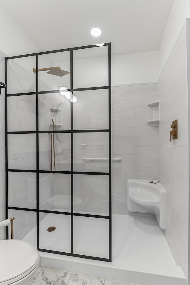 full bath featuring marble finish floor, tiled shower, and toilet