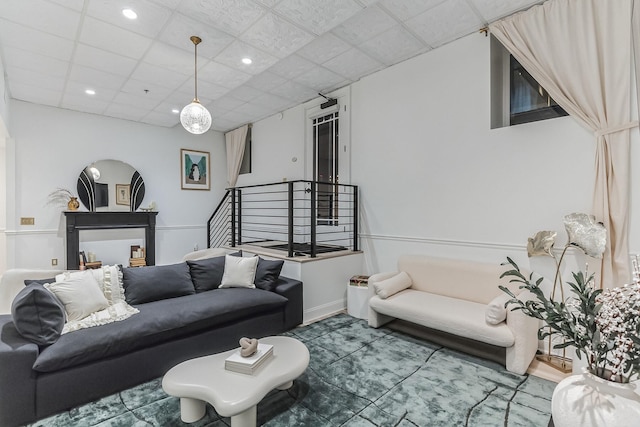 living room featuring baseboards, stairway, a drop ceiling, and recessed lighting