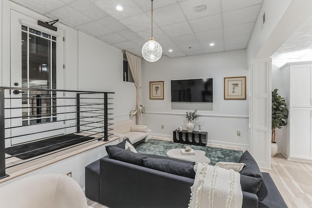 living room with a drop ceiling, recessed lighting, wood finished floors, visible vents, and baseboards