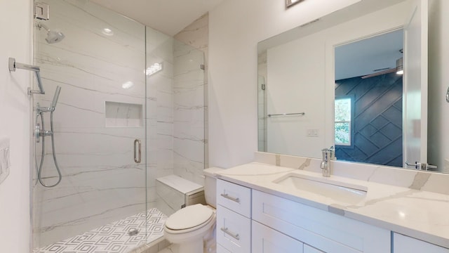 bathroom with toilet, a marble finish shower, and vanity