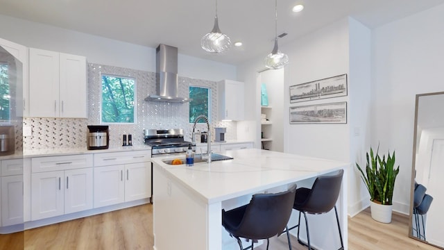 kitchen featuring wall chimney range hood, white cabinets, and gas range