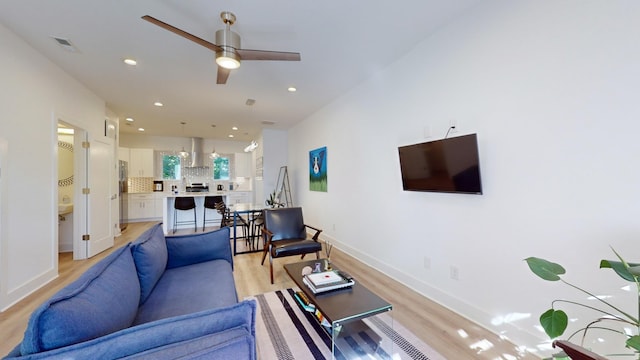 living area with recessed lighting, a ceiling fan, baseboards, visible vents, and light wood-style floors