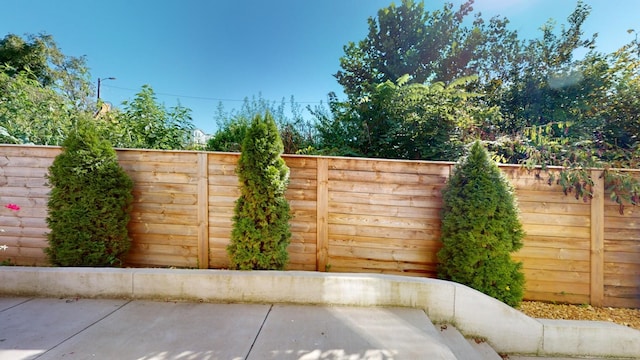 view of gate with a fenced backyard and a patio