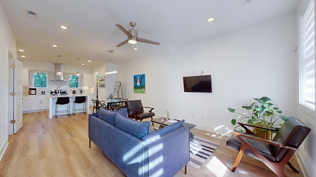 living area with a ceiling fan, recessed lighting, baseboards, and light wood finished floors