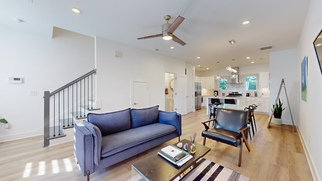 living room with recessed lighting, light wood-style flooring, ceiling fan, baseboards, and stairs