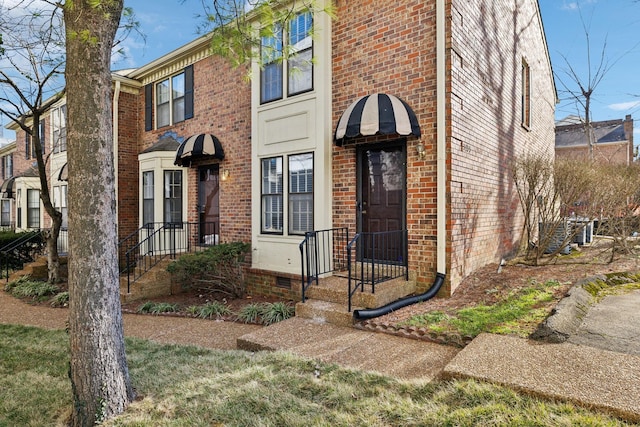 view of property with crawl space, central AC unit, and brick siding