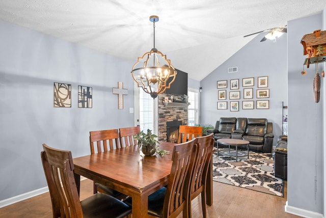 dining area with visible vents, lofted ceiling, wood finished floors, a textured ceiling, and a fireplace