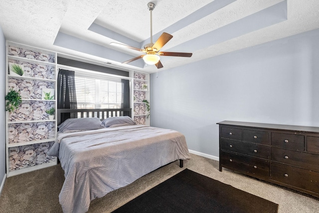 bedroom featuring a textured ceiling, a tray ceiling, baseboards, and light colored carpet