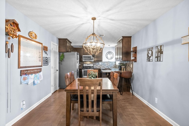 dining space with a textured ceiling, a notable chandelier, visible vents, baseboards, and dark wood-style floors