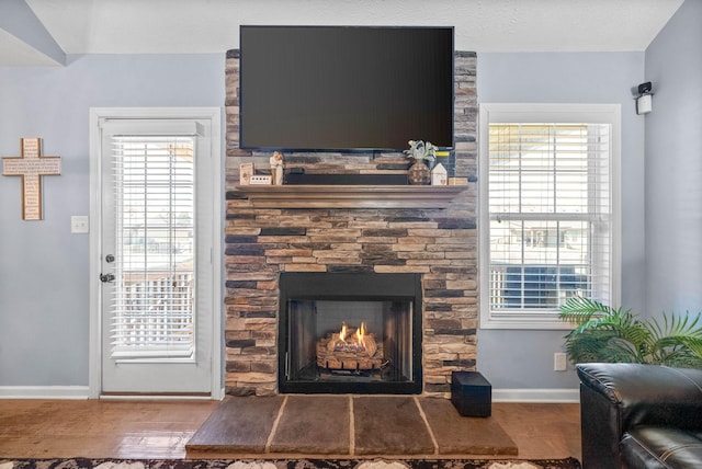 room details with a textured ceiling, a fireplace, wood finished floors, and baseboards