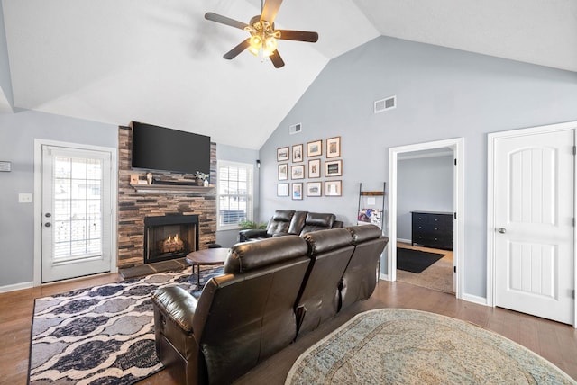 living area featuring a large fireplace, plenty of natural light, wood finished floors, and visible vents